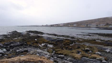 Coastal-landscape-view-on-the-isle-of-Berneray-with-an-incoming-ocean-tide,-gentle-waves-and-spots-of-rain-in-the-outdoor-wilderness-of-Outer-Hebrides-in-Scotland-UK