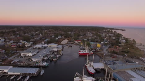 aerial drone flyover of oriental nc harbor and town docks at sunset pull-back shot with diesel spill facing north