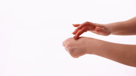 overhead view of hands applying liquid drop to the back of a hand against a white background