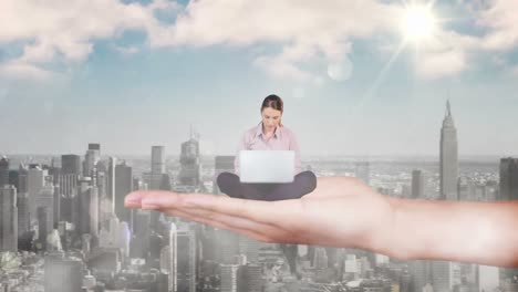 Hand-holding-sitting-businesswoman-focused-on-laptop-above-scyscrapers