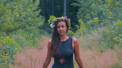 dreamy scene with sensual young woman with flower wreath on head between trees