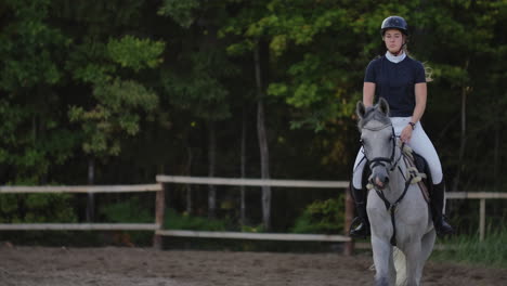 slow motion close up. a female jockey is riding a horse. a female jockey is riding a horse in a corral