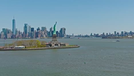 Drone-shot-of-Statue-of-Liberty-Monument-in-front-of-gigantic-new-york-skyline-during-sunny-day-in-summer