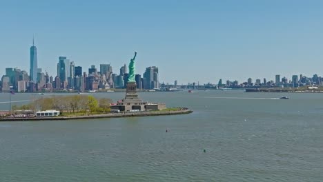 drone shot of statue of liberty monument in front of gigantic new york skyline during sunny day in summer