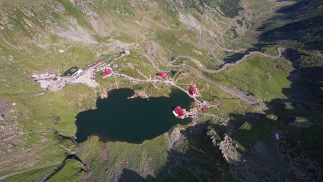 Toma-Aérea-Del-Lago-Balea-Con-La-Sinuosa-Carretera-Transfagarasan-En-Las-Montañas-Fagaras-Al-Amanecer