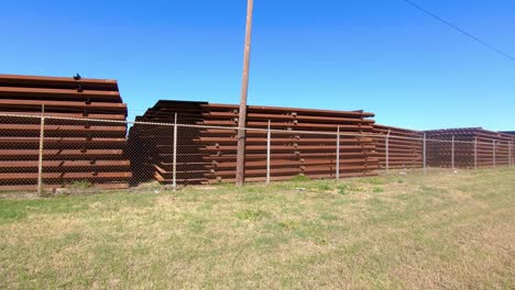 pov pasando por grandes pilas de paneles de metal para construir el muro fronterizo entre texas y méxico