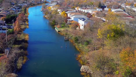 An-aerial-view-over-a-neighborhood-creek,-behind-houses-on-a-sunny-day