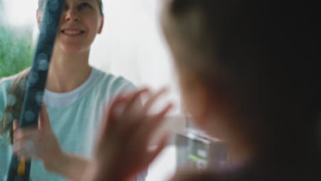 young-mother-cleans-window-with-steam