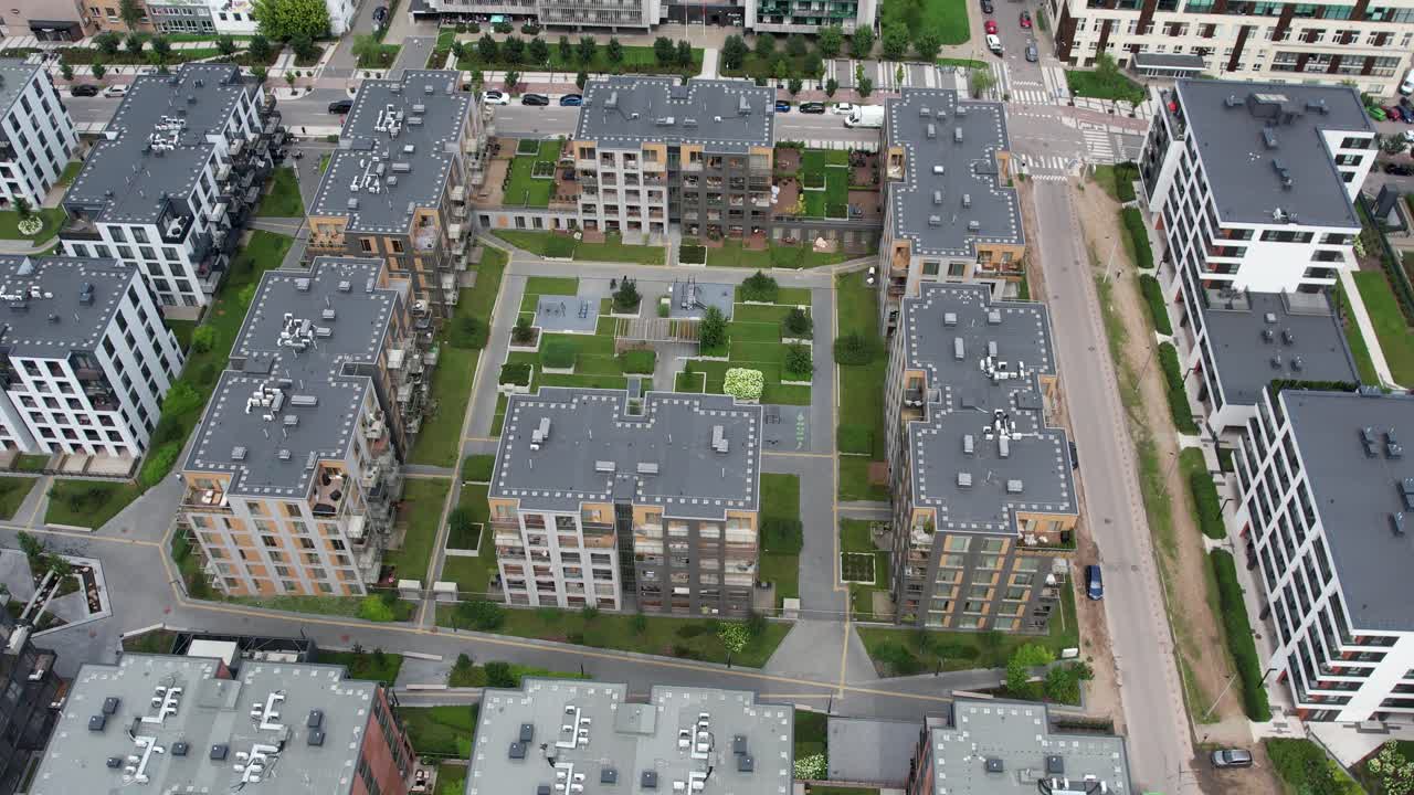 Drone top-down view of modern apartment blocks around a landscaped courtyard in Vilnius, Lithuania, showing rooftops, paths and urban housing layout