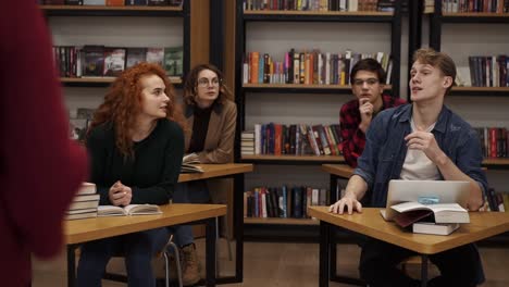 European-college-university-students-group-study-together-prepare-project-make-notes,-happy-young-people-classmates-sitting-at-the-separated-tables-and-discussing-something,-looking-at-the-camera