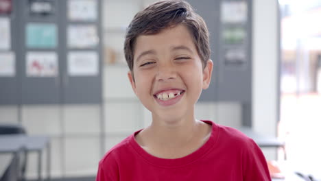 In school, young boy wearing a red shirt smiling in the classroom