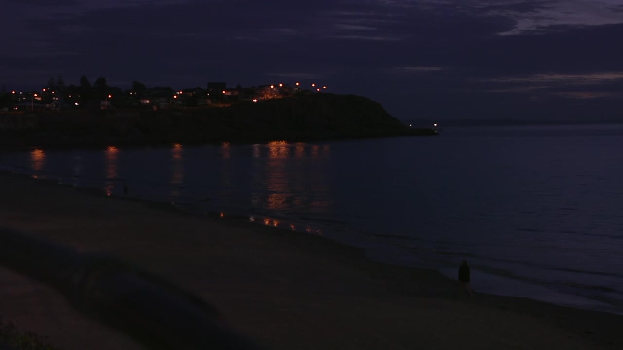 Ilık bir akşamda, karanlıkta, uzaktaki sokak lambalarıyla aydınlatılmış, büyük bir uçurum ve güzel bir arka plana sahip gece sahil.