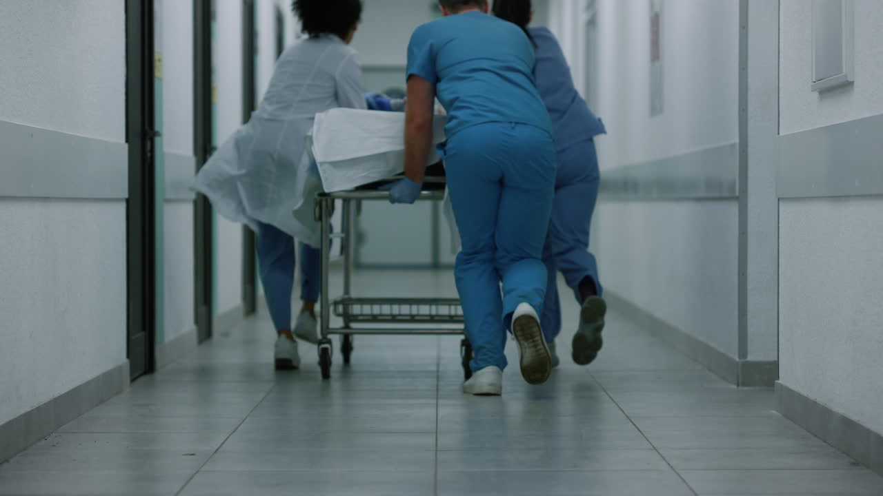 squadra di medici sconosciuti che corrono per il corridoio con barelle a rotelle. medici che trasportano barelle.