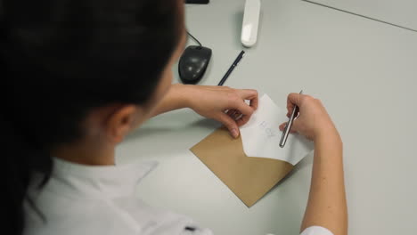 woman putting paper inside of an envelope