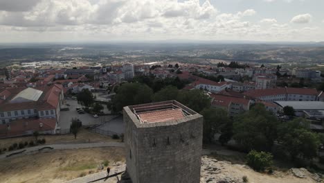 drone flight over the tower of castelo da guarda, guarda castle, in portugal, with rooftops and cityscape in background