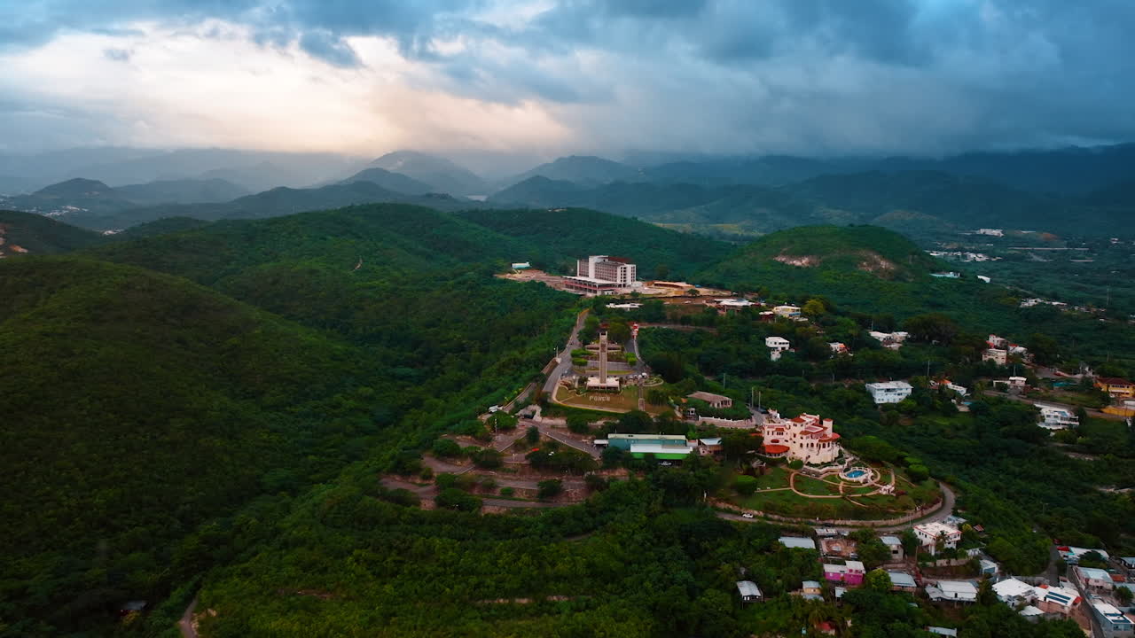 Terbang lebih dekat ke Salib Penjaga di bukit gunung yang hijau subur. Markah tanah Ponce, Puerto Riko. Awan gelap dramatis di atas bebatuan di latar belakang