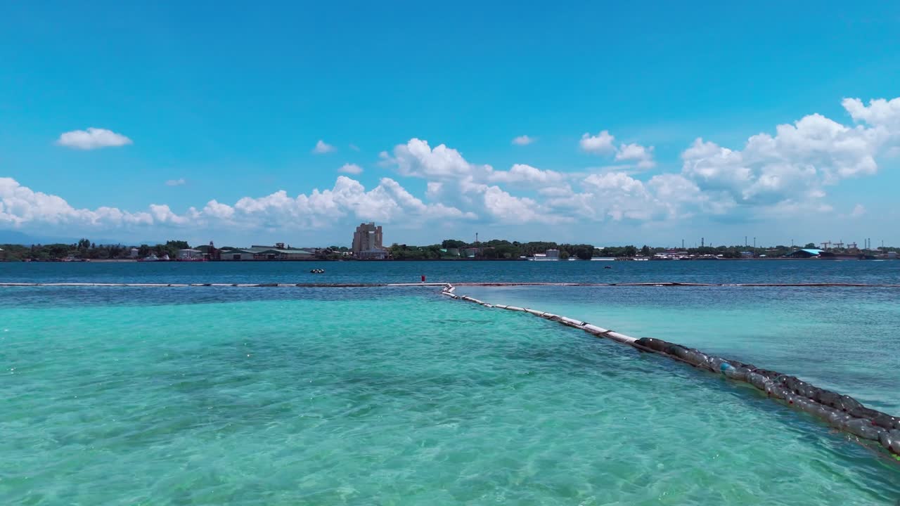 Cinematic 4K drone footage of a clear blue ocean with floating barriers and coastal background. Perfect for travel, environment, and cinematic storytelling