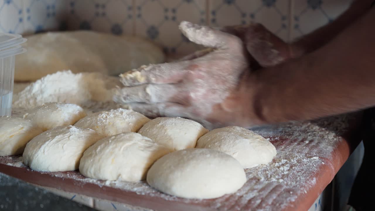 Baker shaping bread loaf dough with flour in hands