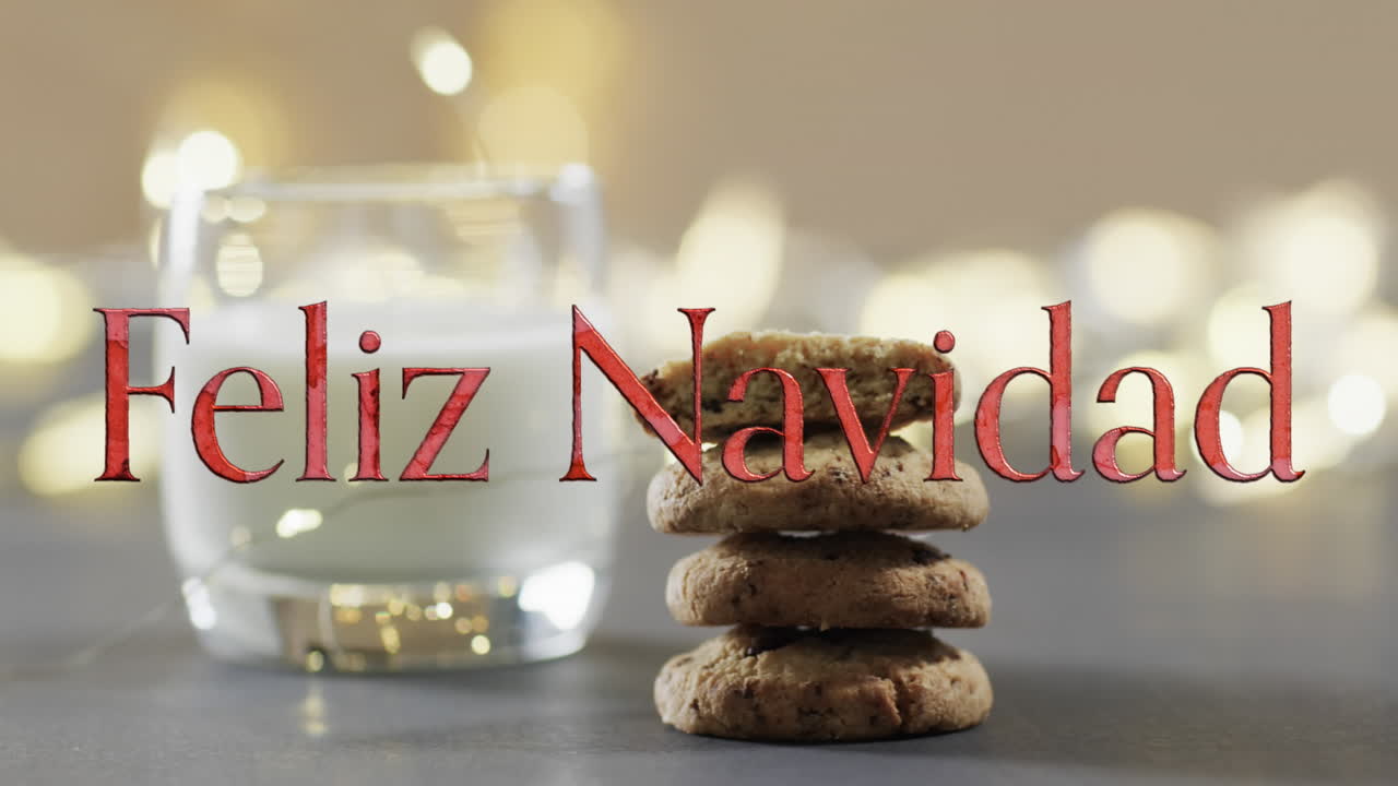 Texto 'Feliz Navidad' en naranja sobre galletas de Navidad y leche con luces bokeh