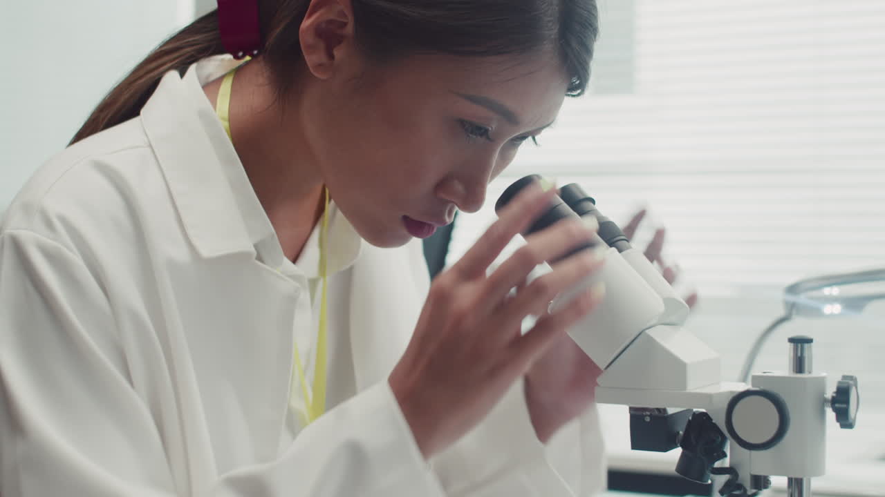 Repairwoman Examining Component of Broken Device in Microscope