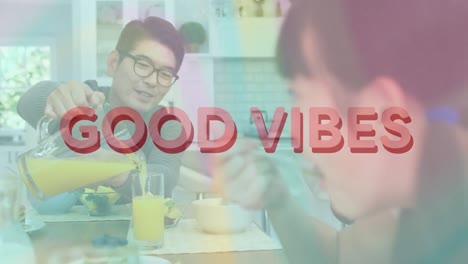 animation of good vibes text over smiling asian family having breakfast