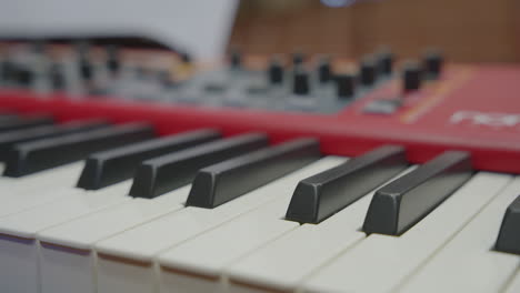 electronic keyboard with black and white keys, red casing, and tactile control knobs in focus