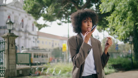 woman dictating voice message on phone standing city park close up. girl talking