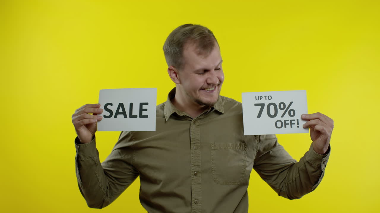 Cheerful man showing Sale word and showing Up To 70 percent Off inscription. Black Friday concept