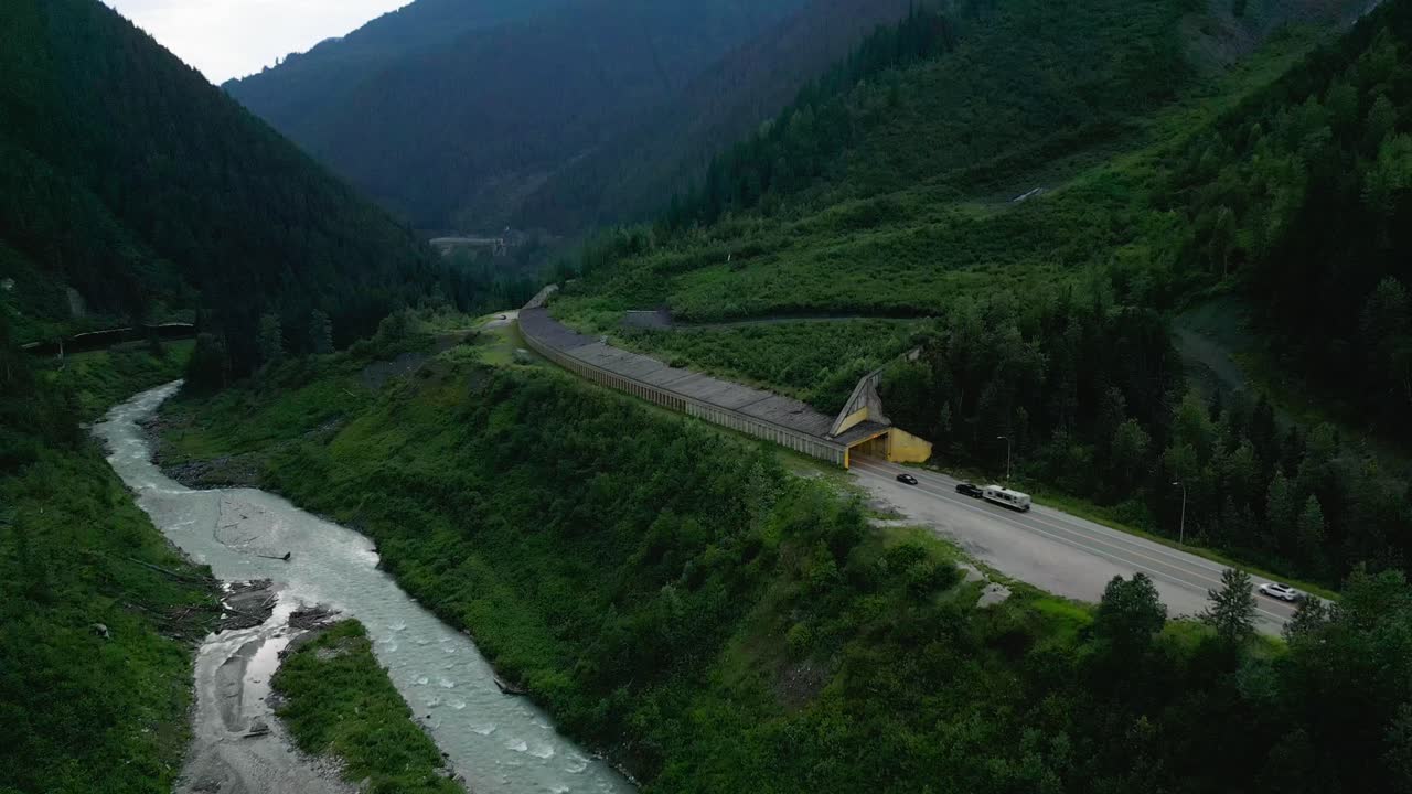 carretera de alta montaña con un río en la parte inferior de un refugio de avalanchas