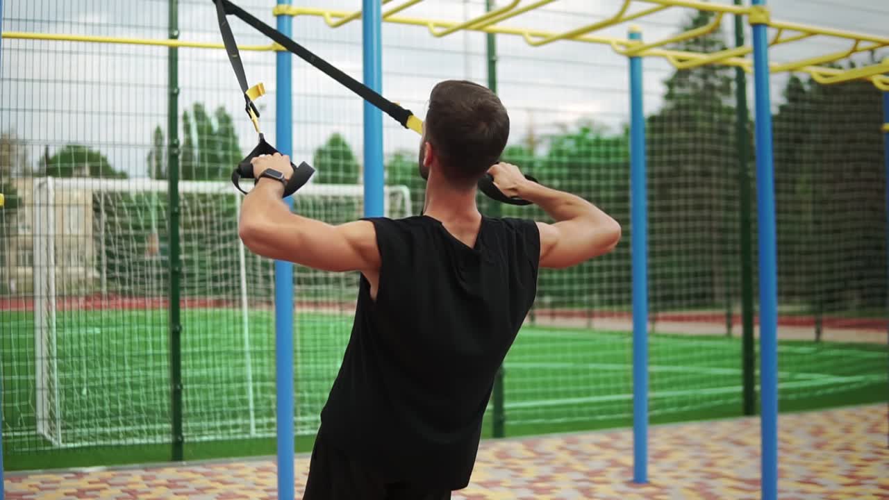 un hombre atlético haciendo ejercicio usando un cinturón de goma para forzar la fuerza del ejercicio en los músculos del pecho y los bíceps