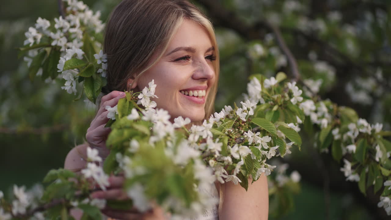 una joven alegre está sonriendo y jugando con ramas en flor de un retrato de cerezo