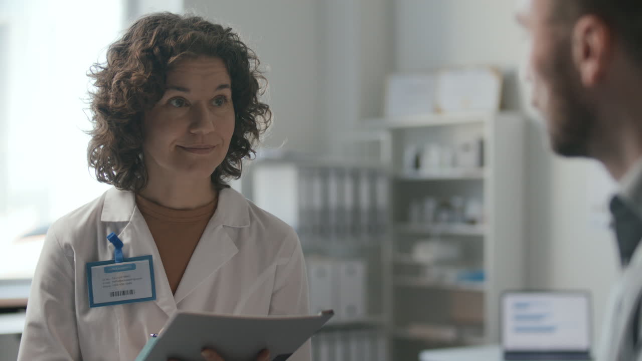 Female Physician Speaking with Patient and Taking Notes during Consultation