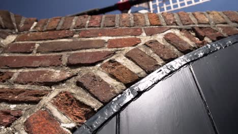 Traditional-old-fashioned-Dutch-windmill-house,-revealing-video-from-bottom-wall-to-upper-wooden-body-pivots,-captured-during-sunshine-day