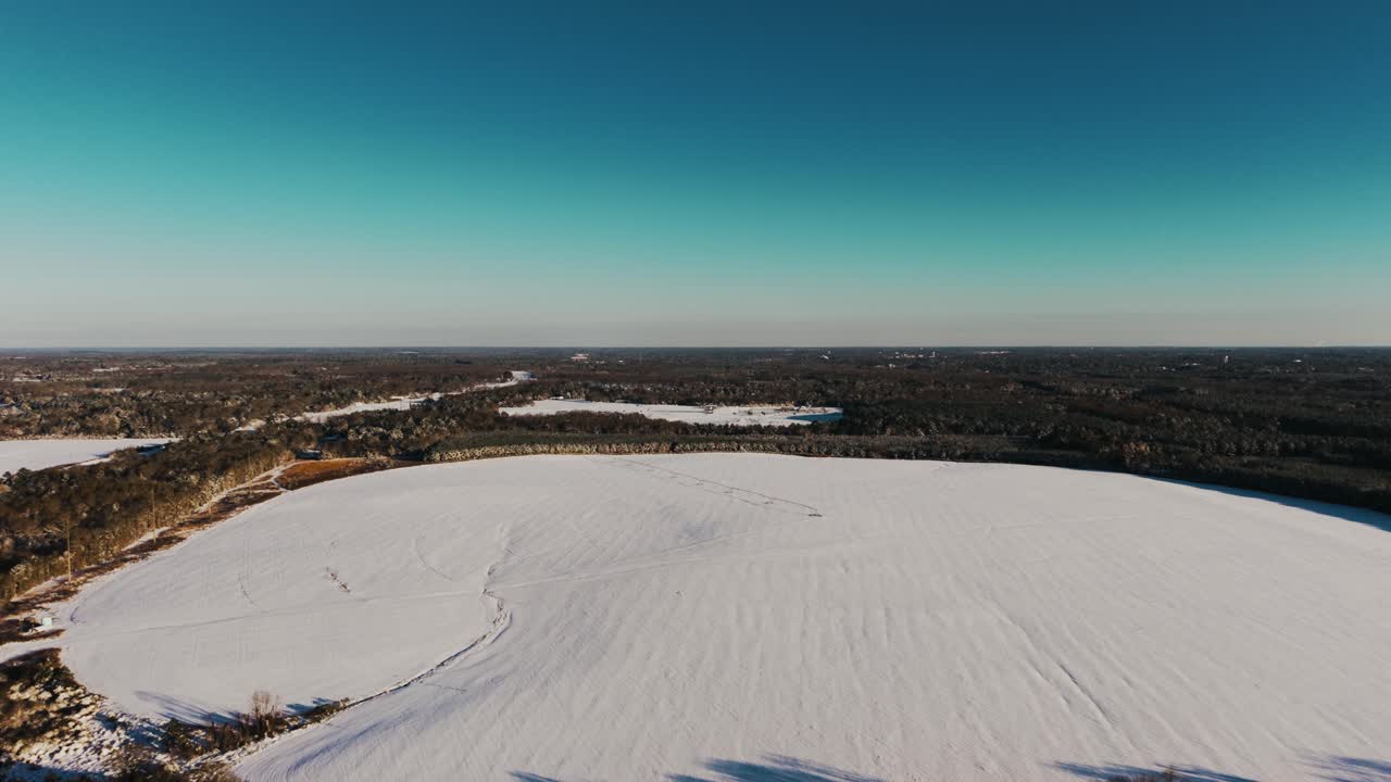 A serene drone shot showcasing a vast, snow-covered farm field in South Georgia. Captured with a slow push-in movement during a rare snowfall event.