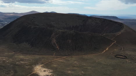 aerial view rising over calderón hondo volcano crater to reveal rugged fuerteventura mountain landscape