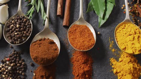 video of spoons with diverse spices lying on grey background