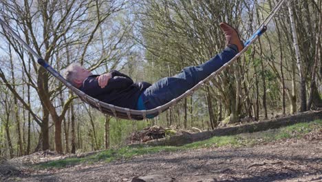 a mature gentleman relaxes on a hammock outside in the nice weather