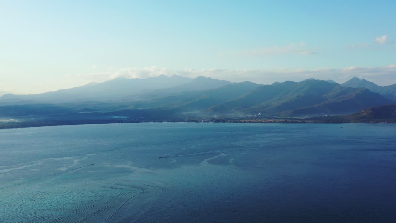 일출을 추적하는 보트와 푸른 바다로 둘러싸인 필리핀 섬의 화산 산 위에 안개 낀 하늘