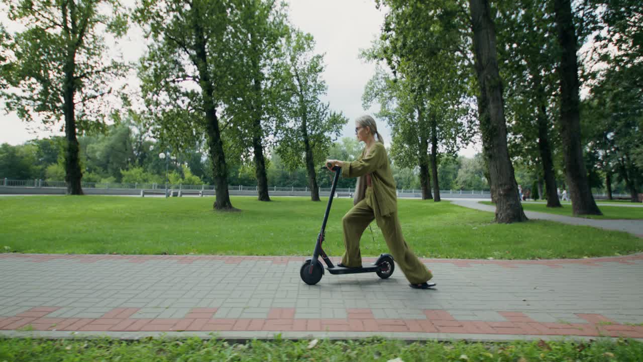 Parkta elektrikli scooter süren kadın