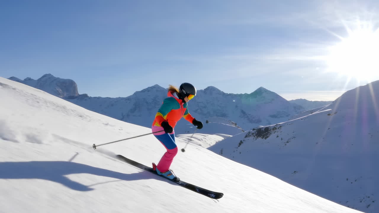 Sciatore che traccia curve su un pendio montano innevato in una giornata di sole