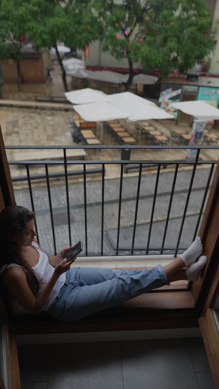 mujer relajándose en un balcón en un día de lluvia