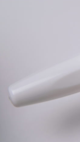 man taps on cap by fingers and opens nasal spray with white plastic cap on light background extreme close view