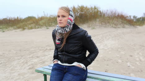 young girl is sitting on a bench near the sea