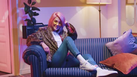 beautiful young caucasian woman wearing fur coat and sunglasses resting on sofa in vintage room at home