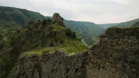 drone ascending over ancient ruins of tmogvi fortress revealing mtkvari river in georgia