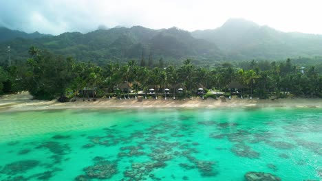 Lenta-Ondulación-Del-Agua-Contra-La-Costa-De-Rarotonga,-Islas-Cook-Con-Montañas-Al-Fondo