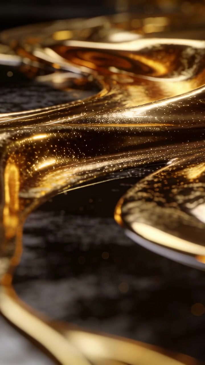 Video verticale: Liquido viscoso dorato che si espande e si muove su una base scura, con luce calda che rivela lo scintillio.