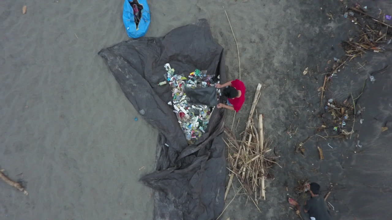 Environmental volunteers clean beach of garbage litter, aerial view