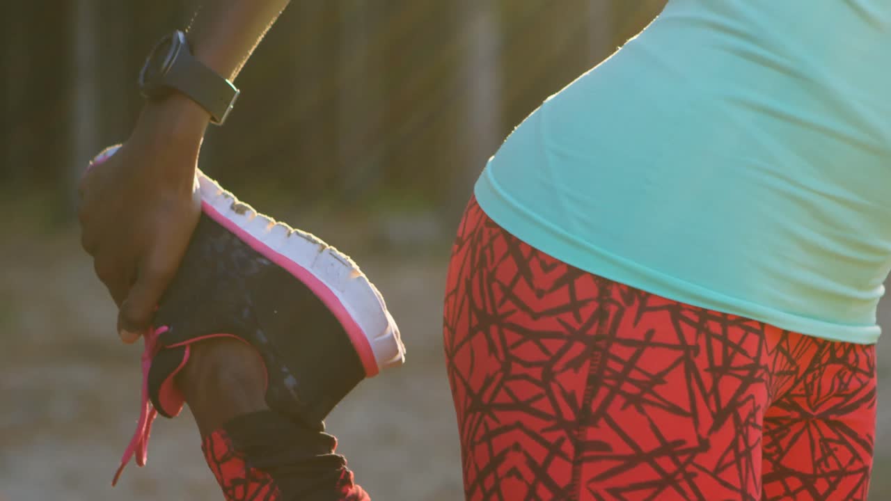 atleta femenina realizando ejercicios de estiramiento mientras escucha música en el bosque 4k