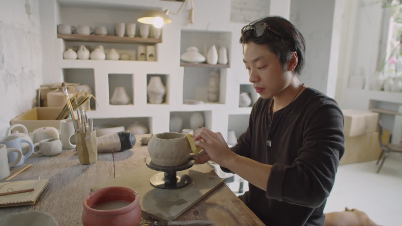 Young Asian Ceramist Using Sponge for Making Mug in Pottery Workshop